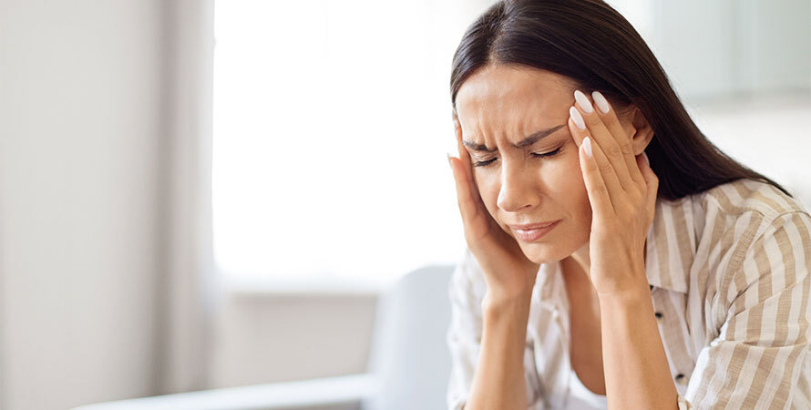 woman suffering from stress migraine holding head in pain showing the connection between tension and migraine attacks
