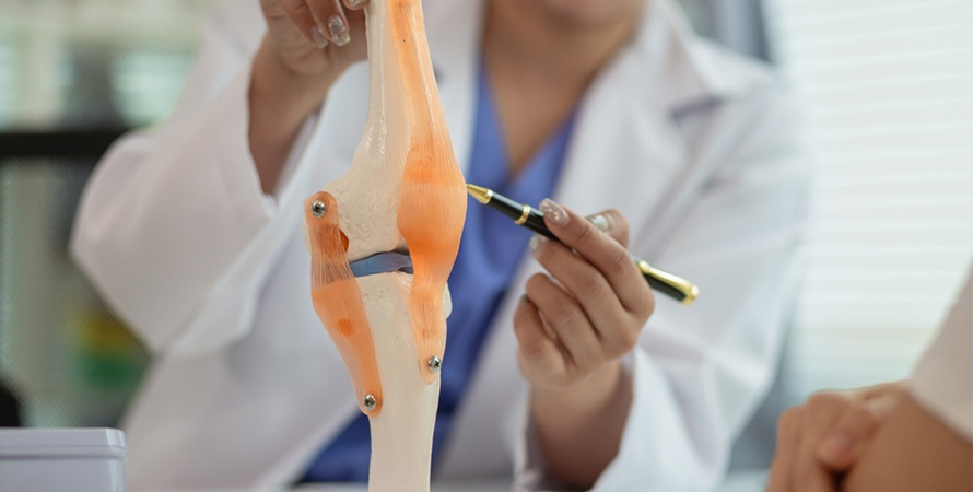 woman experiencing extreme fatigue and joint pain sitting on bed holding knee